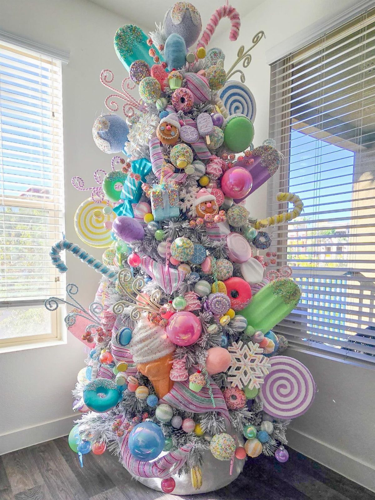 Flocked Christmas tree decorated with oversized colorful candy and dessert ornaments.