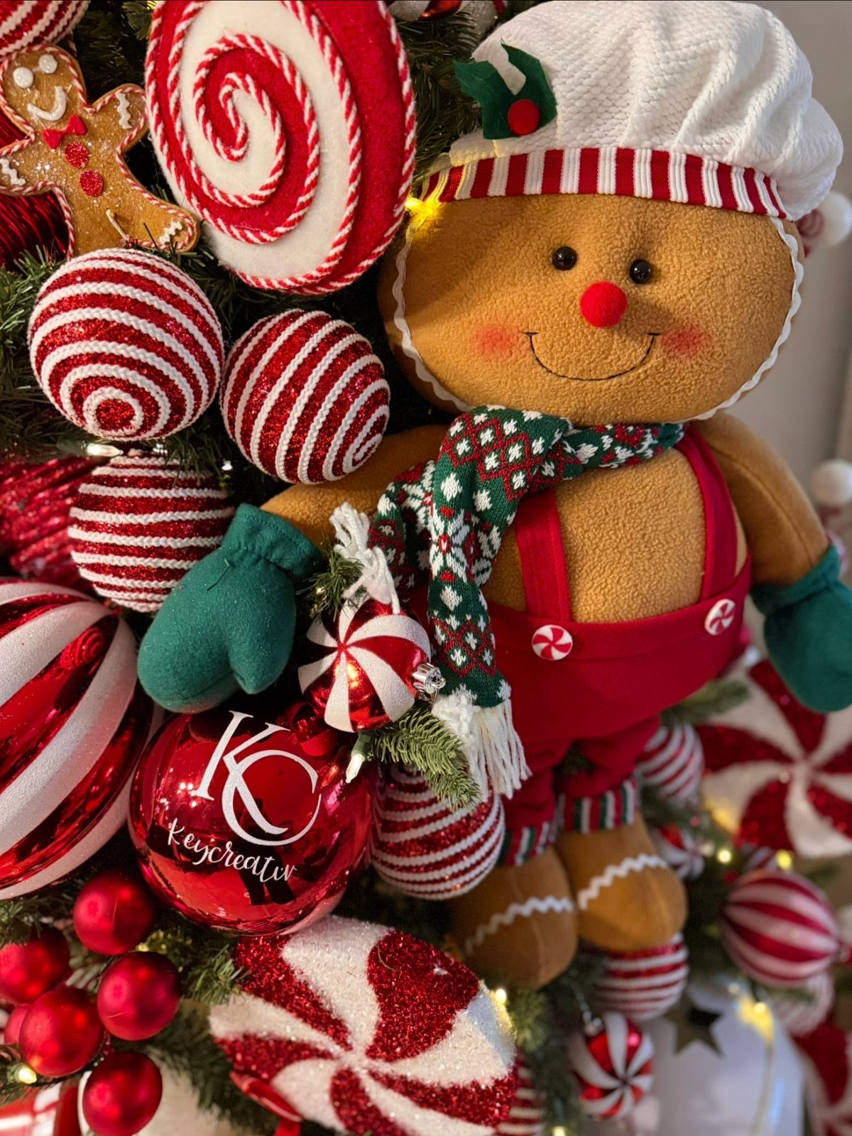 Plush gingerbread man ornament surrounded by red and white peppermint candy decorations.
