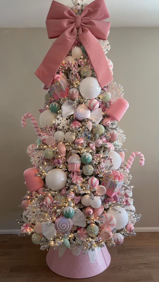 White Christmas tree decorated with oversized pink and mint candy ornaments and a bow.