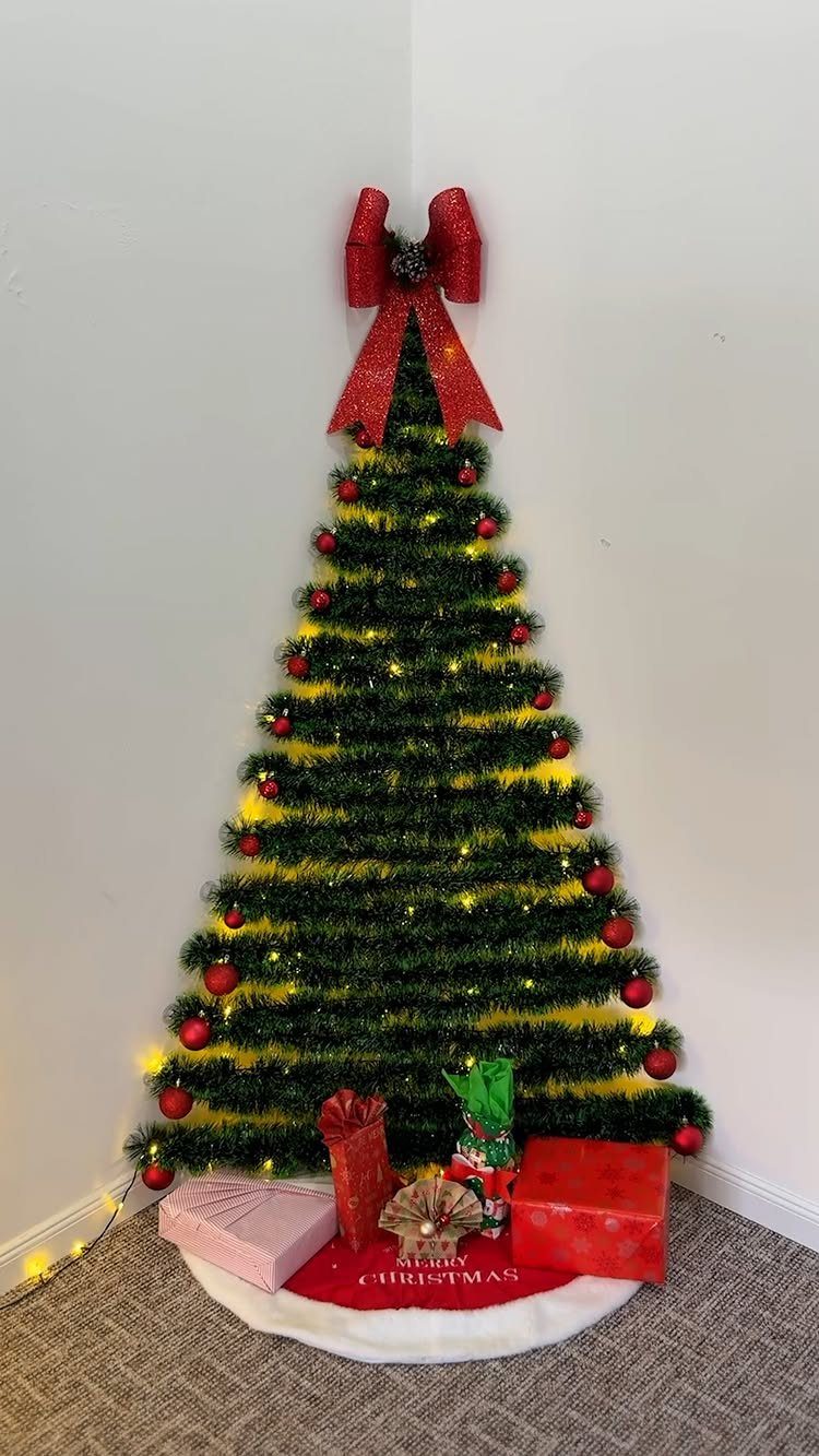 Green Christmas tree with red ornaments, yellow lights, and a large red bow topper.