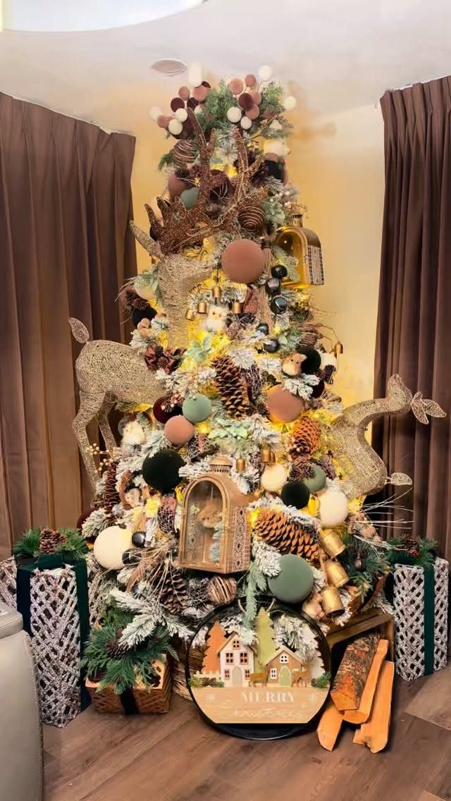 Decorated Christmas tree with pinecones, wooden ornaments, and glittery deer figures in a room.
