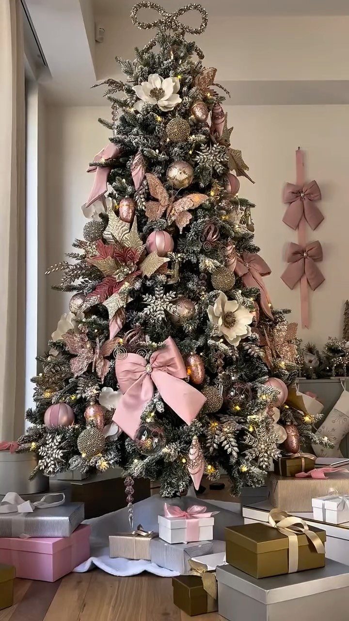 Decorated Christmas tree with oversized pink bows and gold ornaments and wrapped gifts.