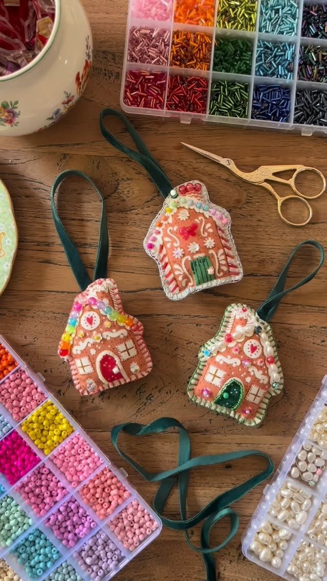 Beaded gingerbread house ornaments on a wooden table with colorful seed beads.