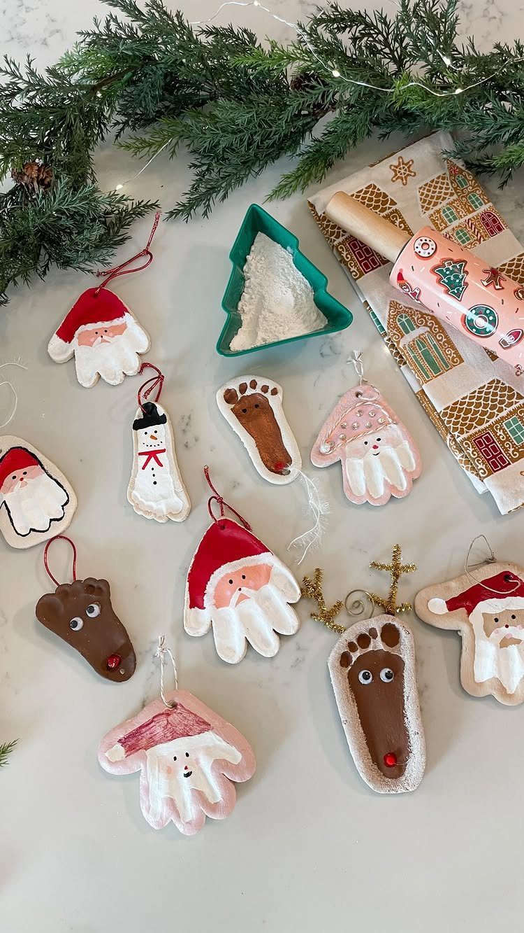 Handmade clay handprint and footprint ornaments painted as Christmas characters on white surface