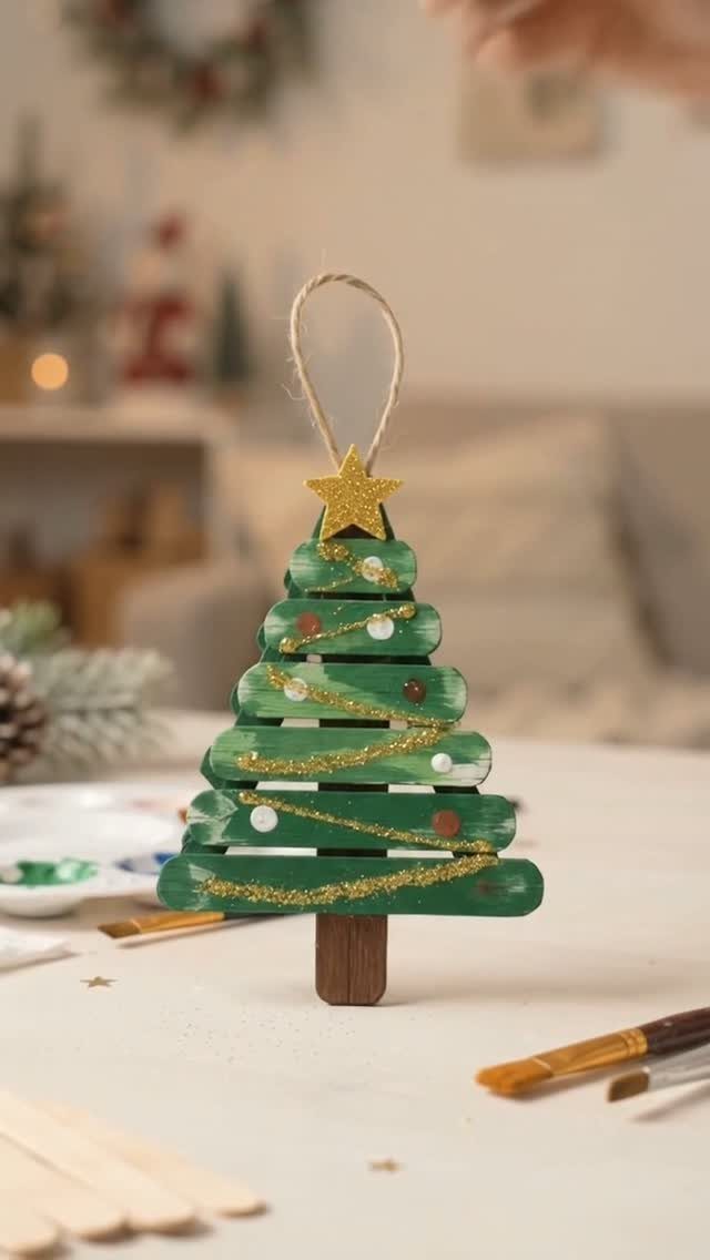 Green wooden popsicle stick Christmas tree ornament with gold glitter and star topper.
