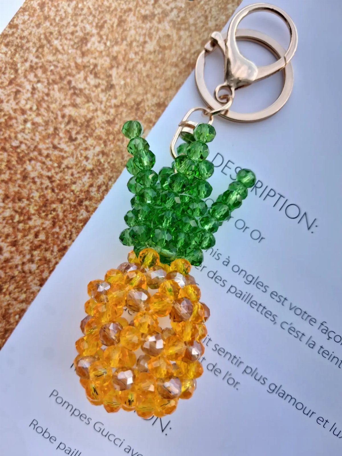 Beaded pineapple keychain with yellow body and green leaves on white paper