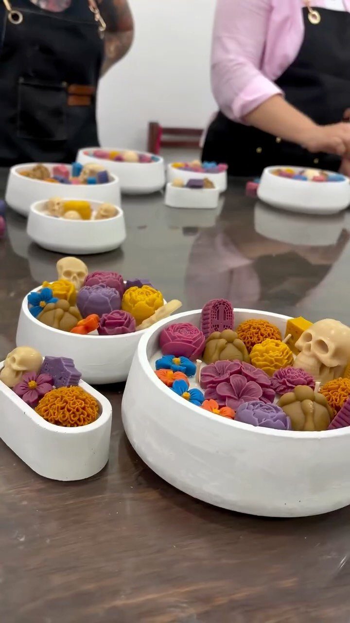 White bowls filled with colorful clay skulls and flowers for Day of the Dead.