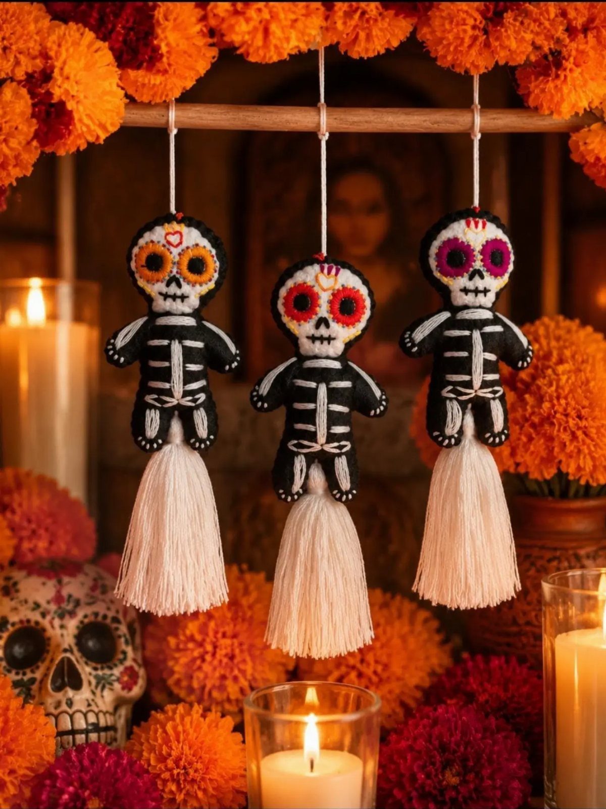 Skeleton dolls hanging among orange marigolds and lit candles for Day of the Dead.