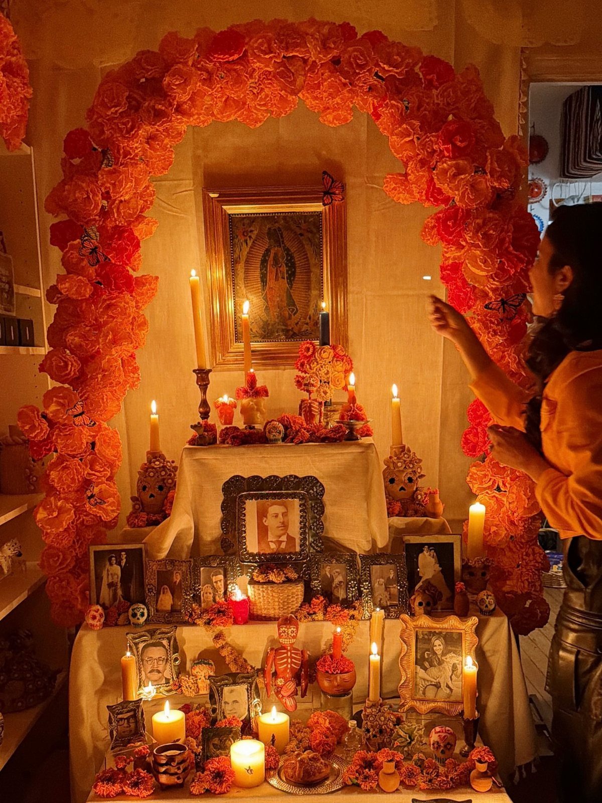 Day of the Dead altar with orange marigolds, candles, and framed family photos.
