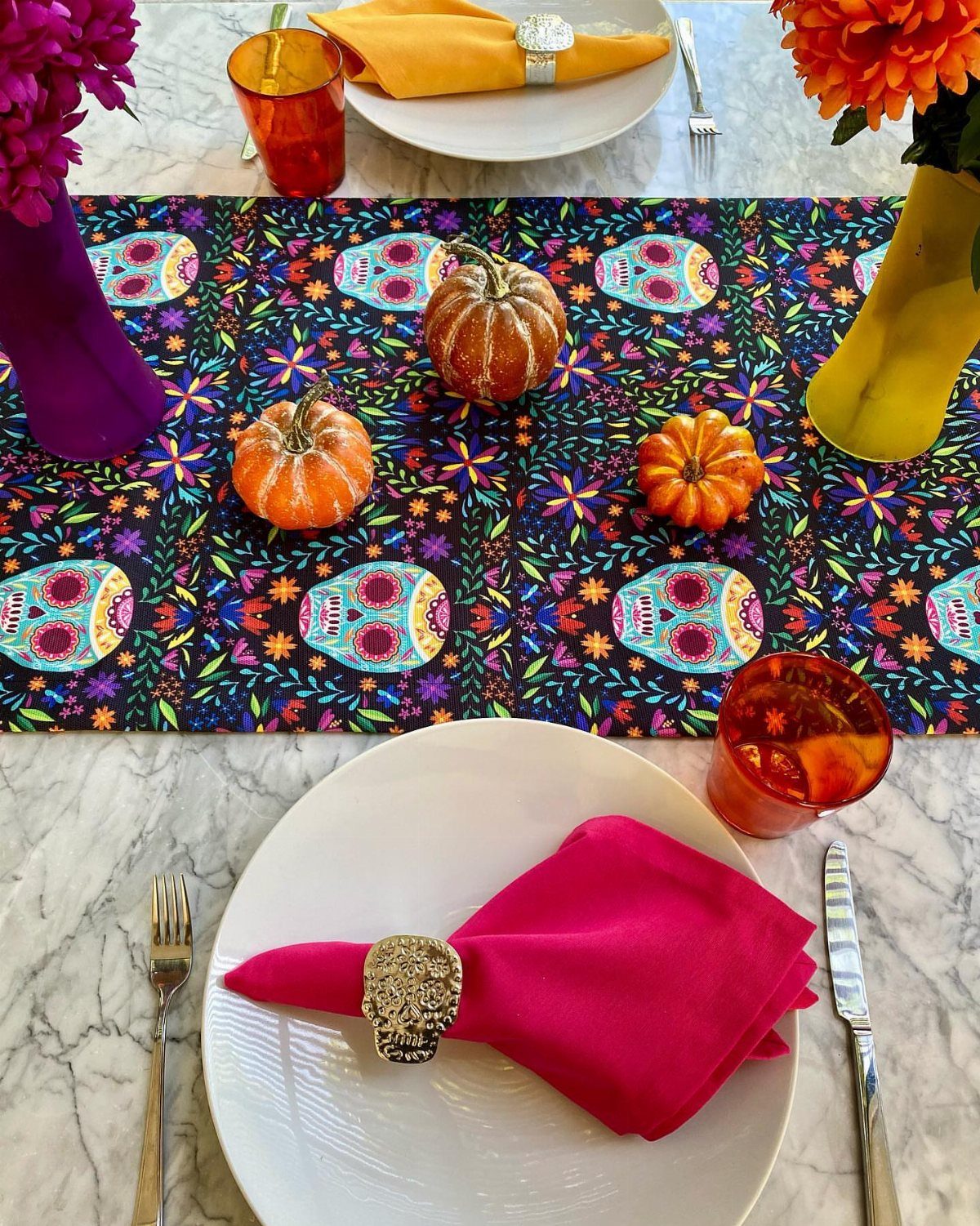 Day of the Dead table setting with sugar skull runner and small pumpkins.