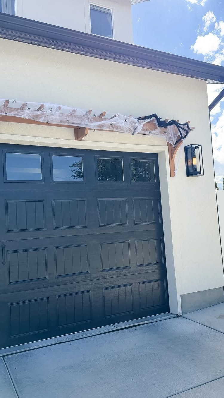 Garage door decorated with white spiderwebs and a black spider on the beam
