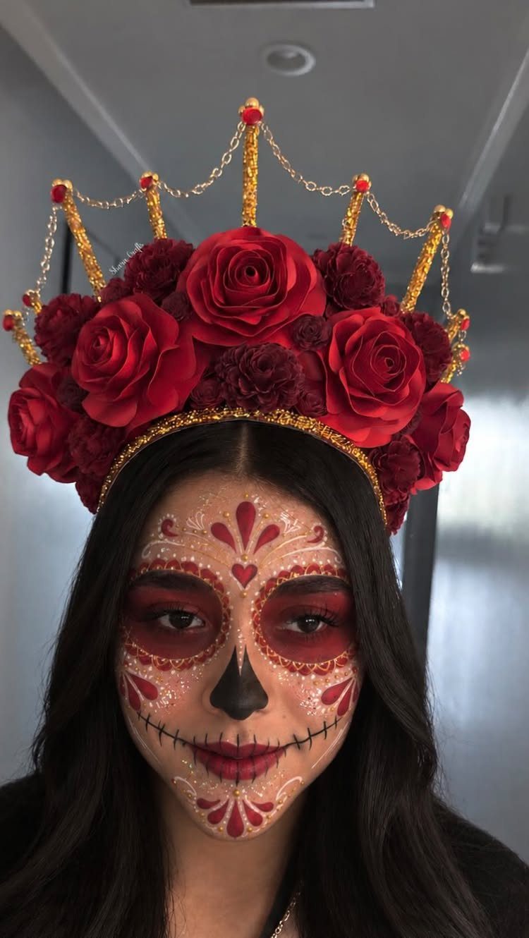 Woman with sugar skull makeup wearing a red rose and gold chain crown.