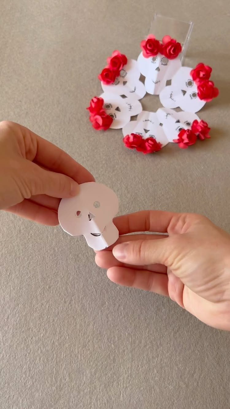 Hands folding a paper sugar skull to create a decorative floral rosette.