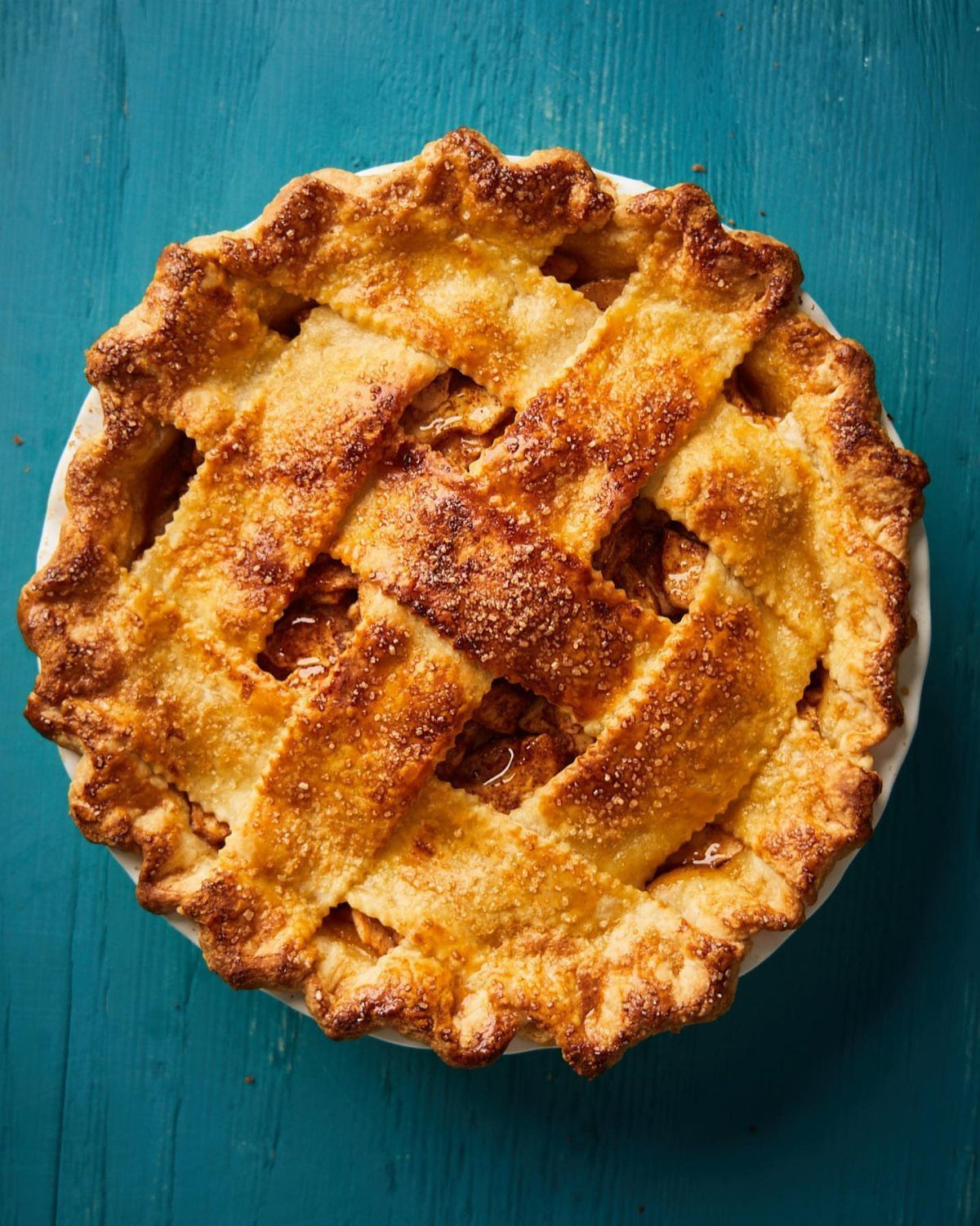 Apple pie with a golden lattice crust on a blue wooden background.