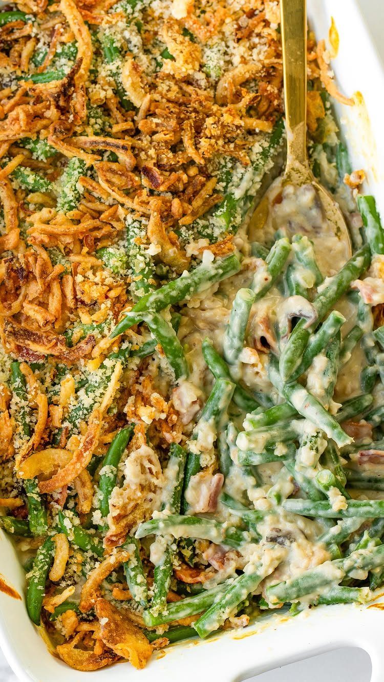 Green bean casserole with creamy sauce and fried onions in a white dish.