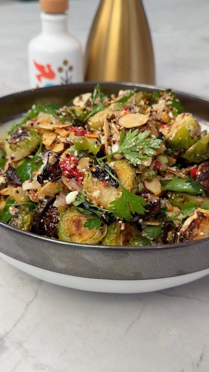 Roasted Brussels sprouts with sliced almonds and parsley in a grey bowl.