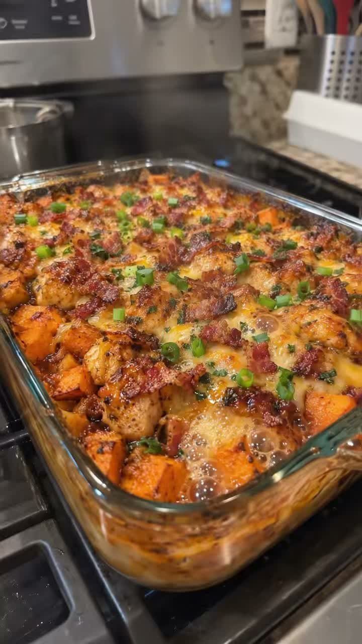 Sweet potato casserole with melted cheese, bacon, and green onions in glass dish.