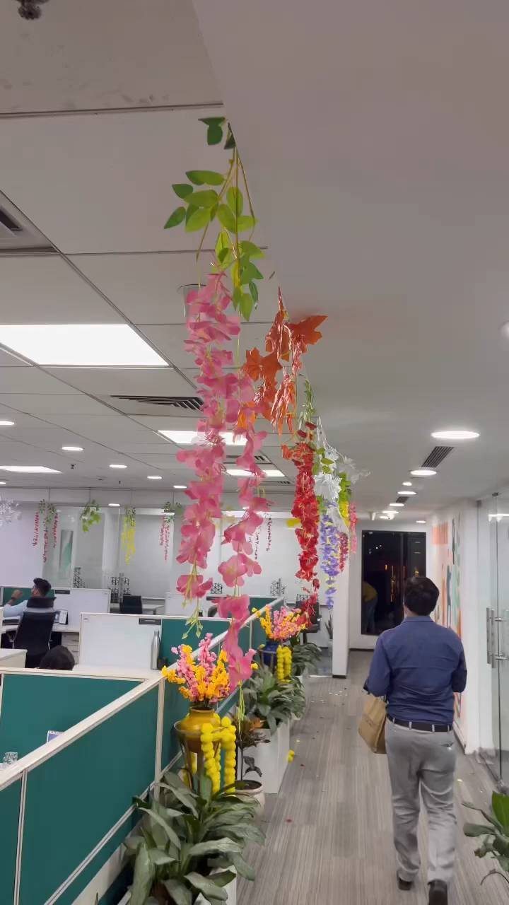 Office hallway decorated with colorful hanging floral garlands and yellow flower arrangements.