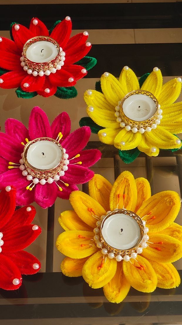 Colorful flower-shaped decorative diyas with tea light candles and pearl accents.