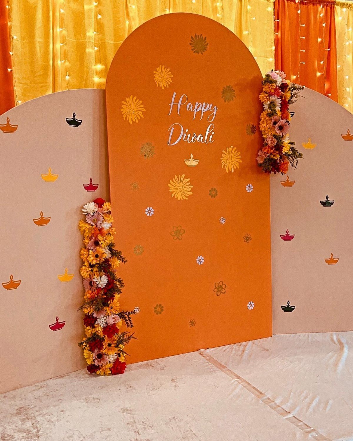 Orange Diwali backdrop with floral garlands and fairy lights in an office setting