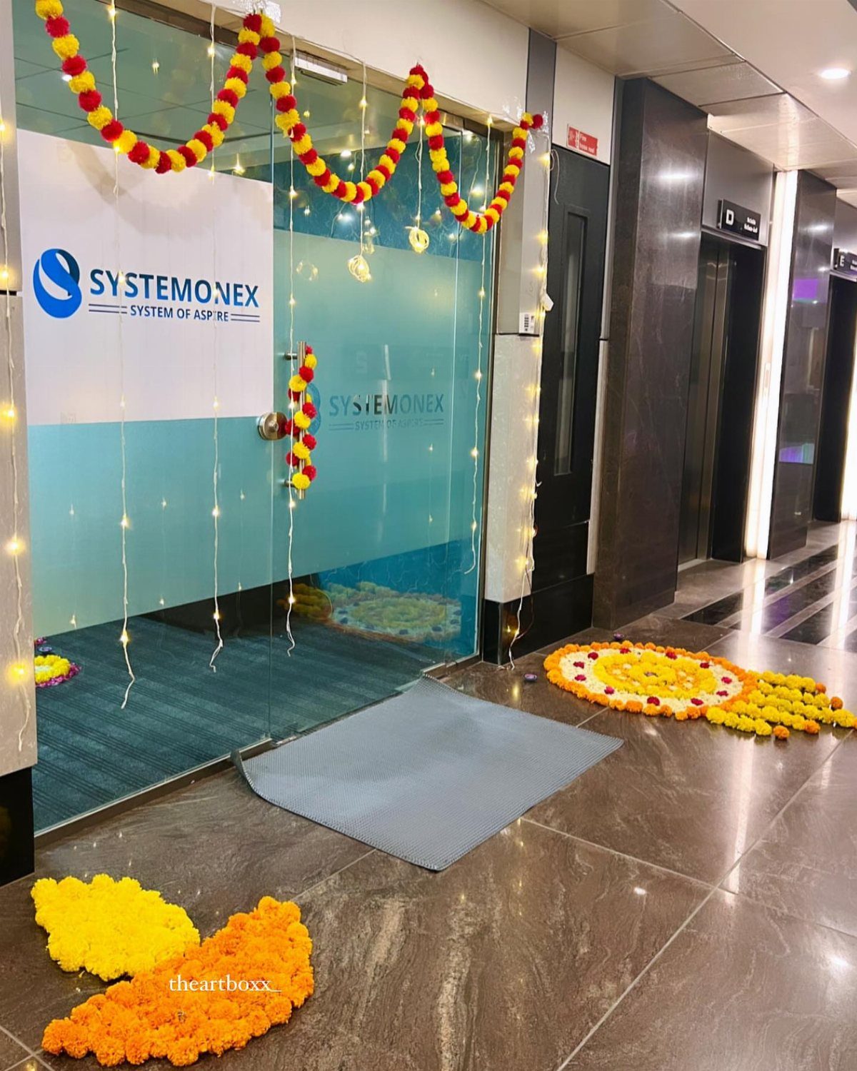 Office entrance decorated with marigold flower garlands and floral rangoli on the floor