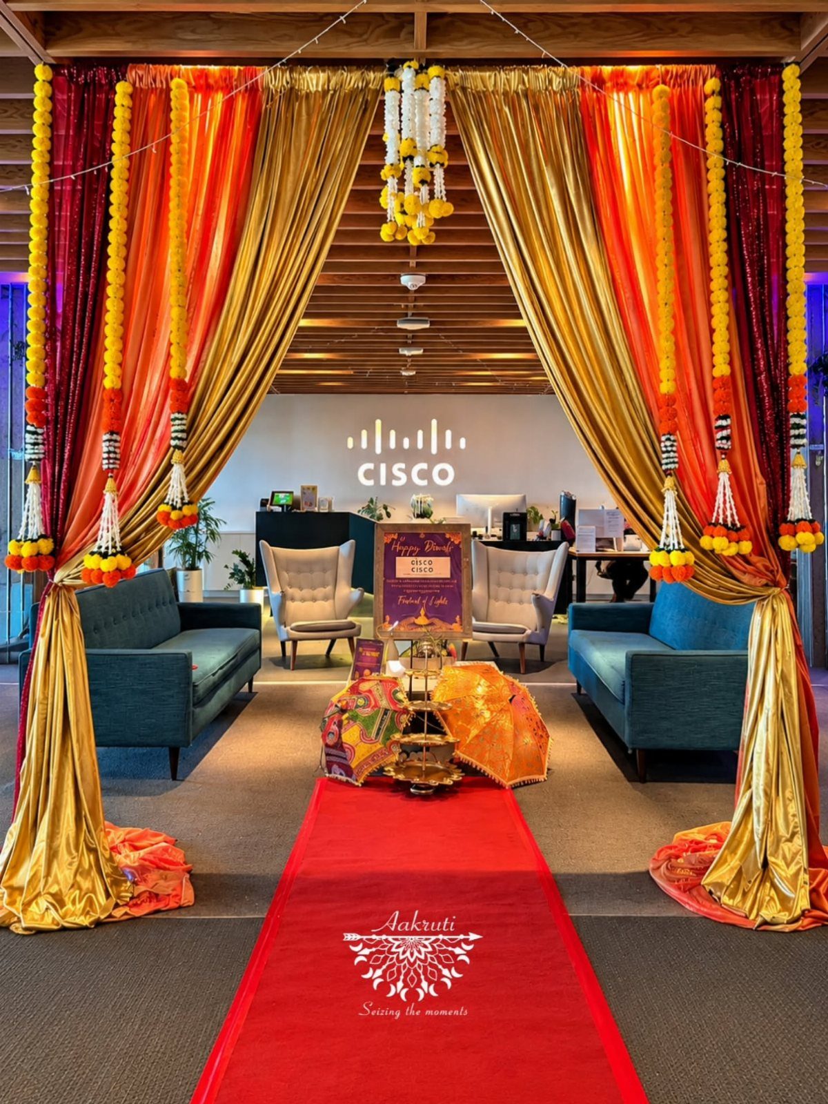 Office interior decorated with gold drapes, marigold garlands, and a red carpet runner.