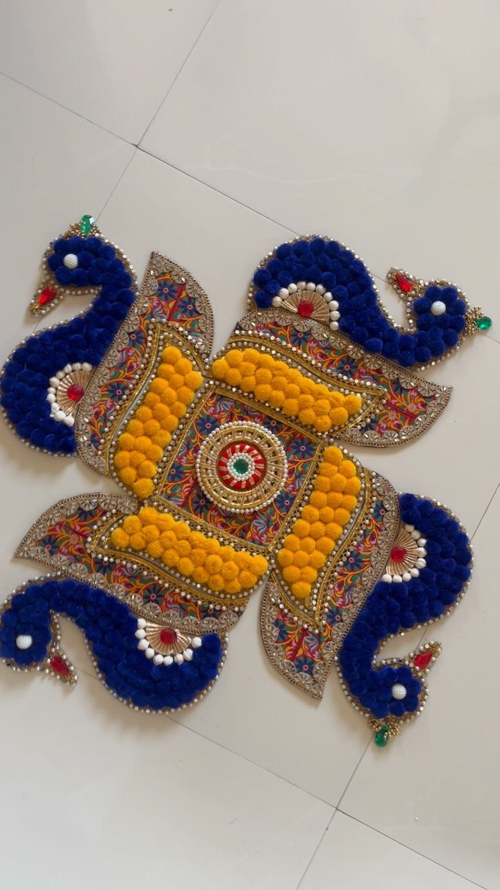 Colorful rangoli design with blue peacocks and yellow flowers on white tiled floor.