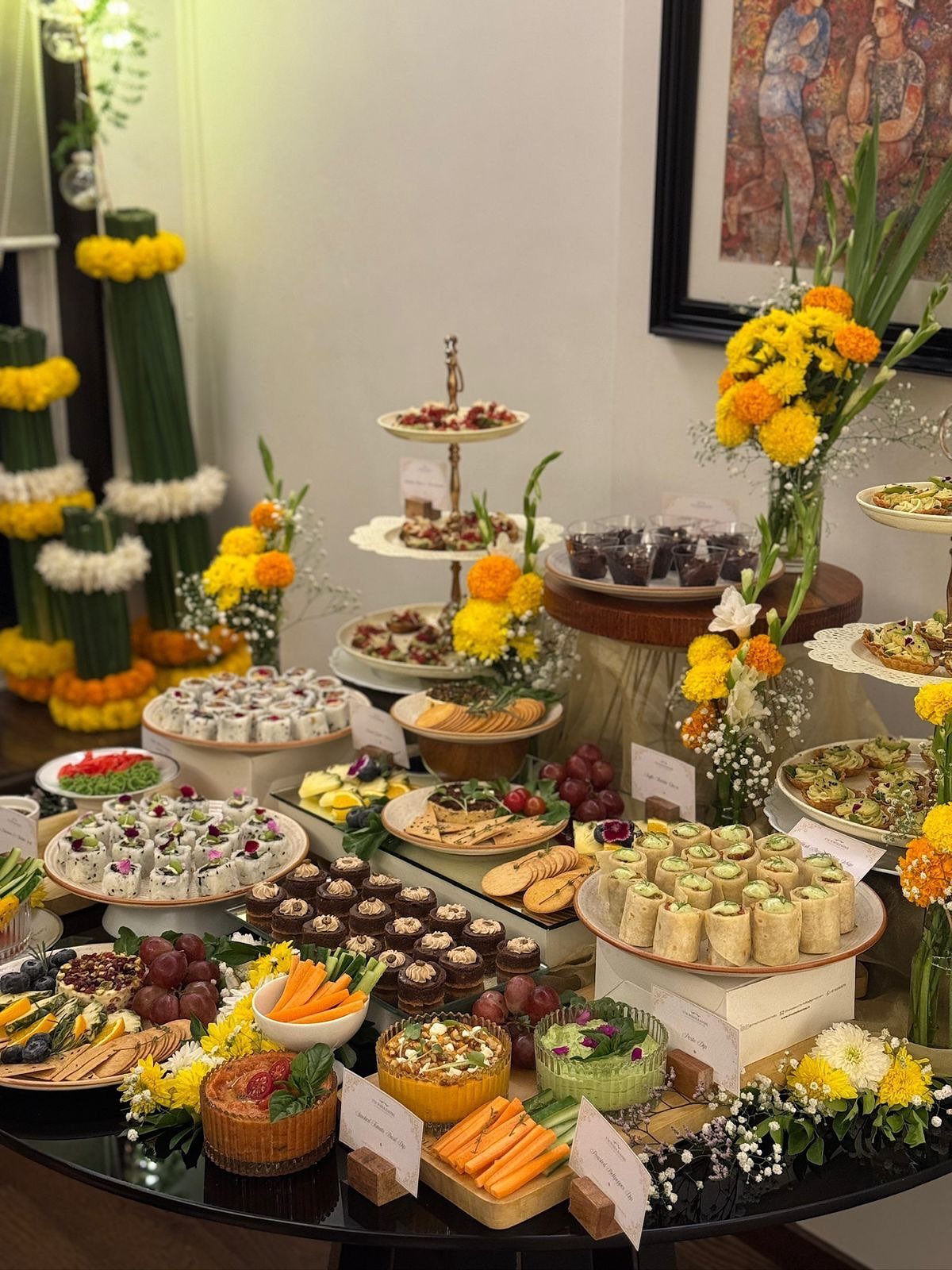 Festive snack table with assorted appetizers and yellow marigold flower decorations.