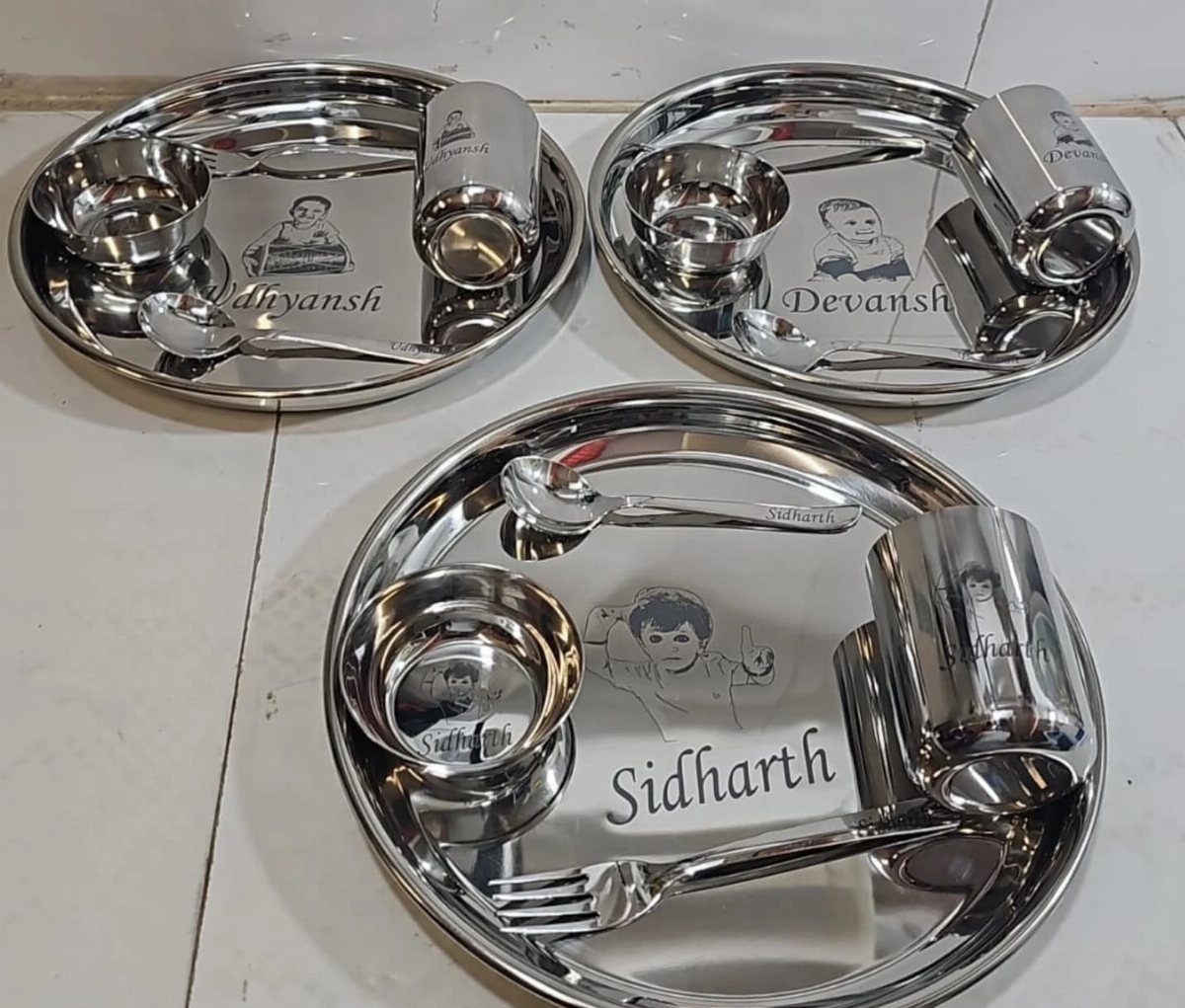 Personalized stainless steel plates with etched names and portraits of children.
