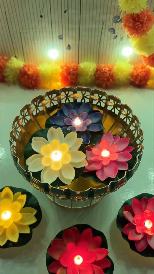 Lotus-shaped floating candles in a gold bowl with marigold garlands in background