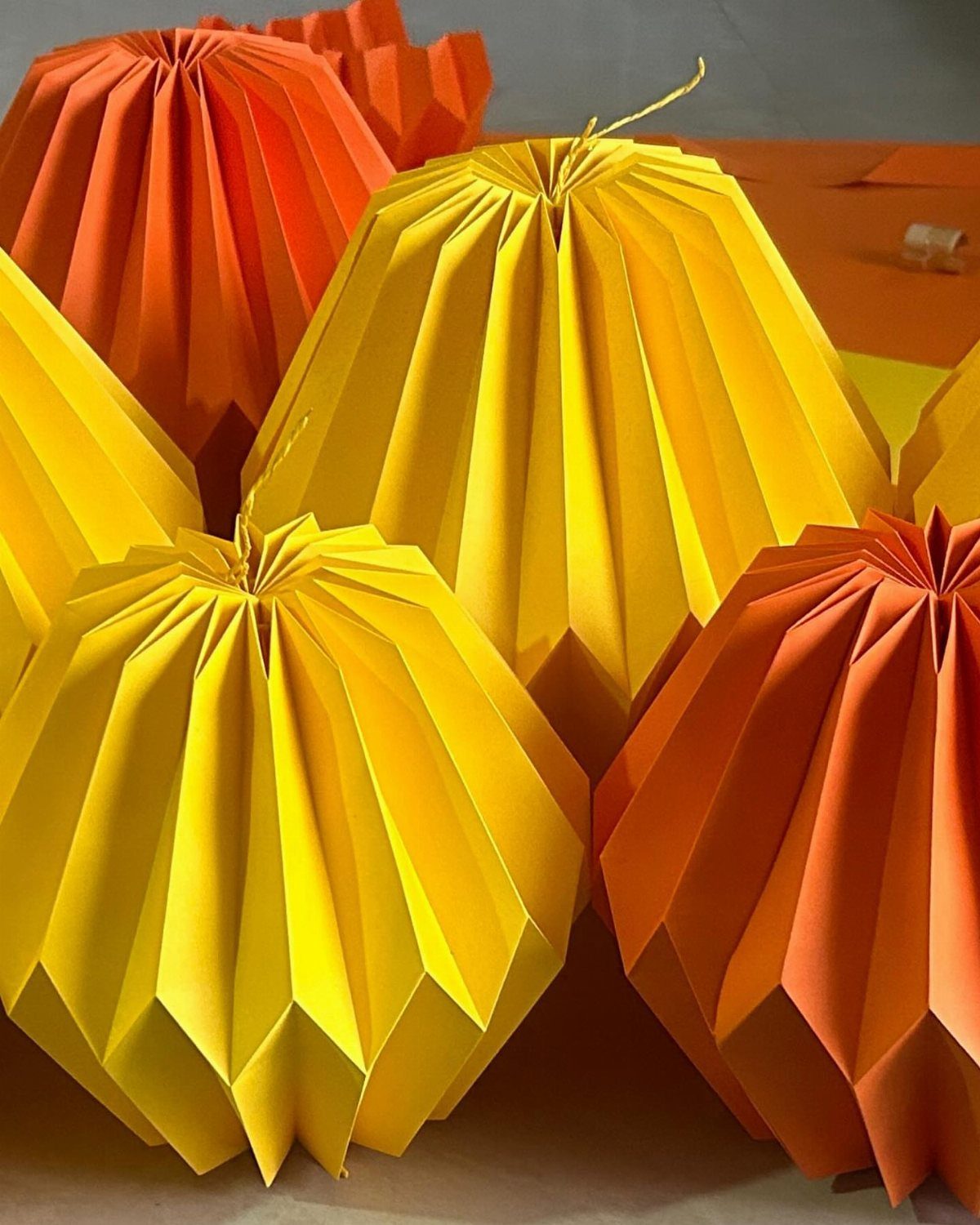 Yellow and orange pleated paper lanterns arranged together for festive home decoration.