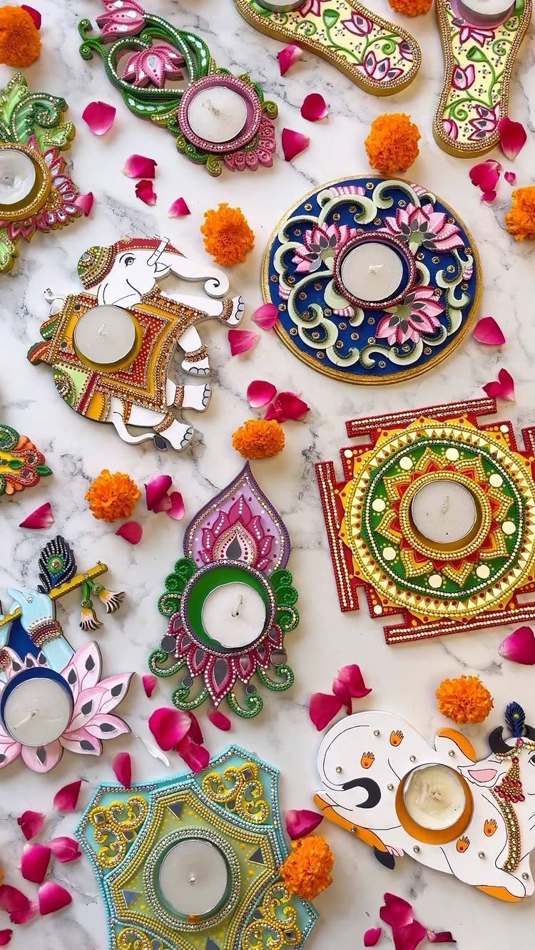 Colorful ornate tea light candle holders with flower petals on white marble surface.