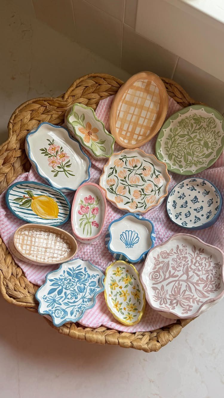 Hand-painted ceramic trinket dishes with floral patterns in a woven wicker basket