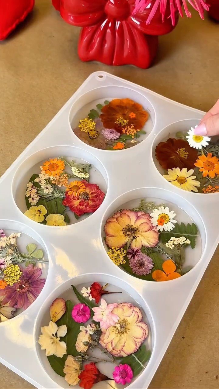 Dried colorful flowers being arranged in clear resin within a white silicone mold.