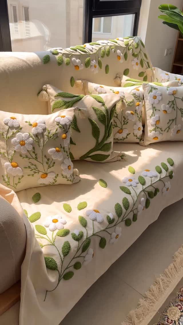 Cream sofa and pillows with textured white daisy and green leaf punch needle embroidery.