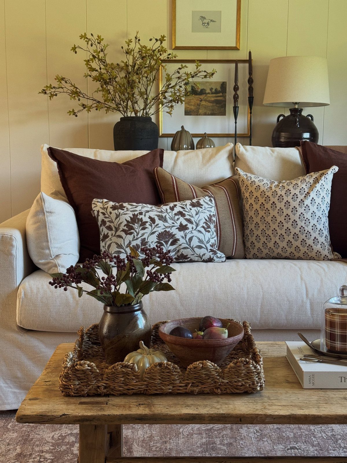 Brown and beige patterned fall pillows on a cream sofa with rustic decor.