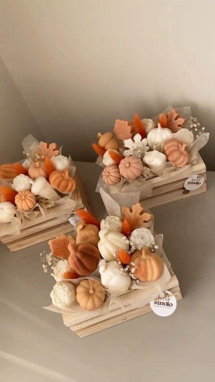 Three wooden crates filled with miniature orange and white pumpkins and autumn leaves.