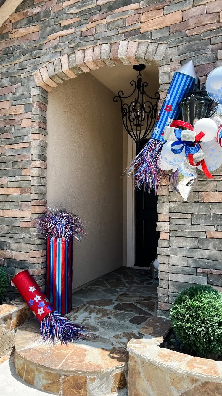 Large red, white, and blue firecracker decorations decorating a stone house porch entrance.
