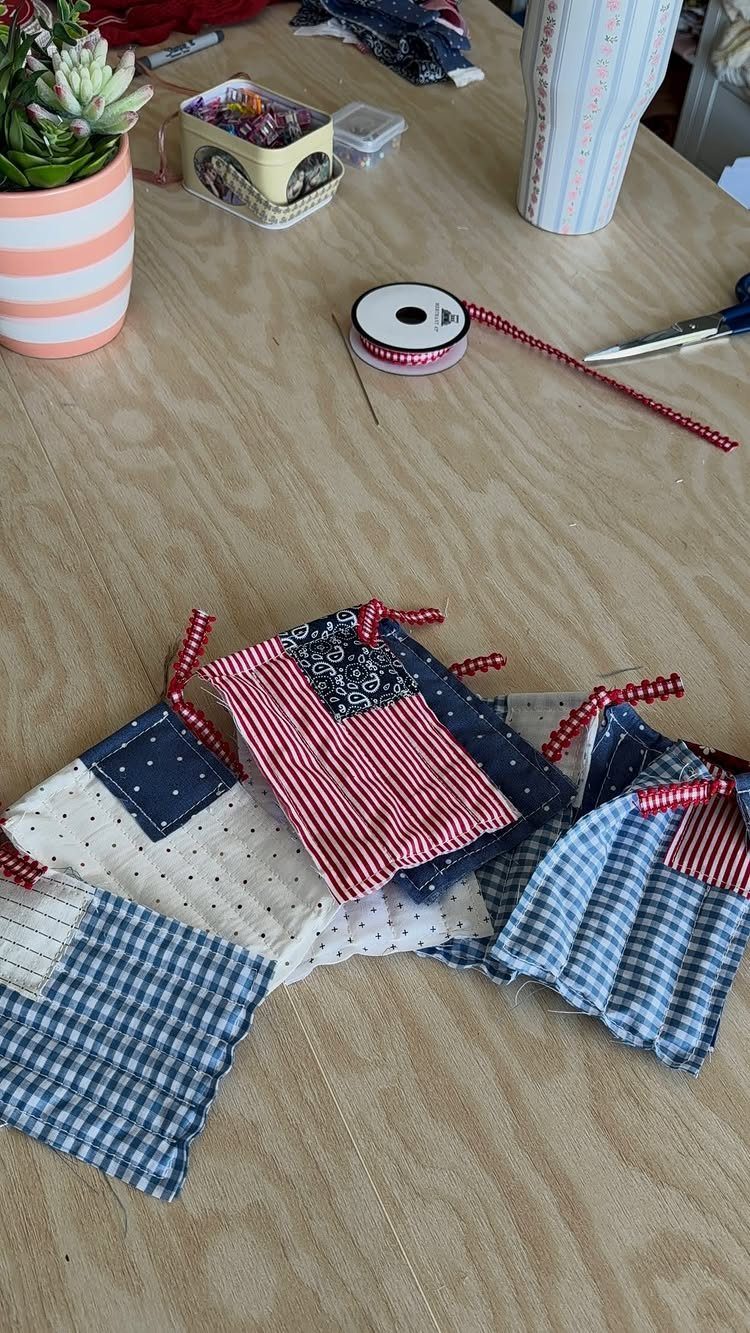 Handmade patriotic fabric scrap flags in red, white, and blue on a wooden table.
