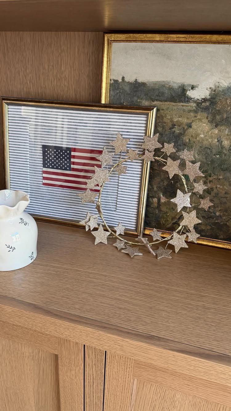 Silver glittery star wreath on a wooden shelf next to an American flag.
