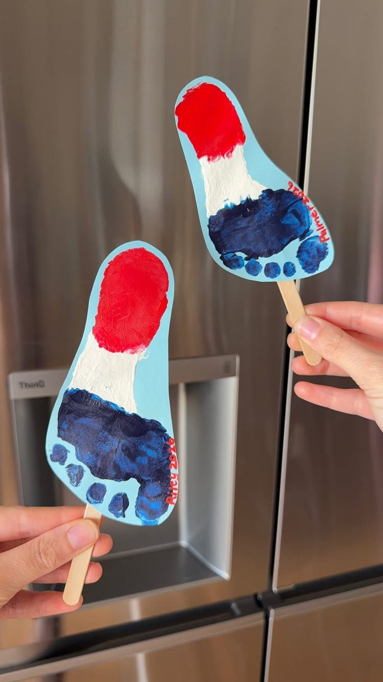Footprint crafts on popsicle sticks painted in red, white, and blue patriotic colors.