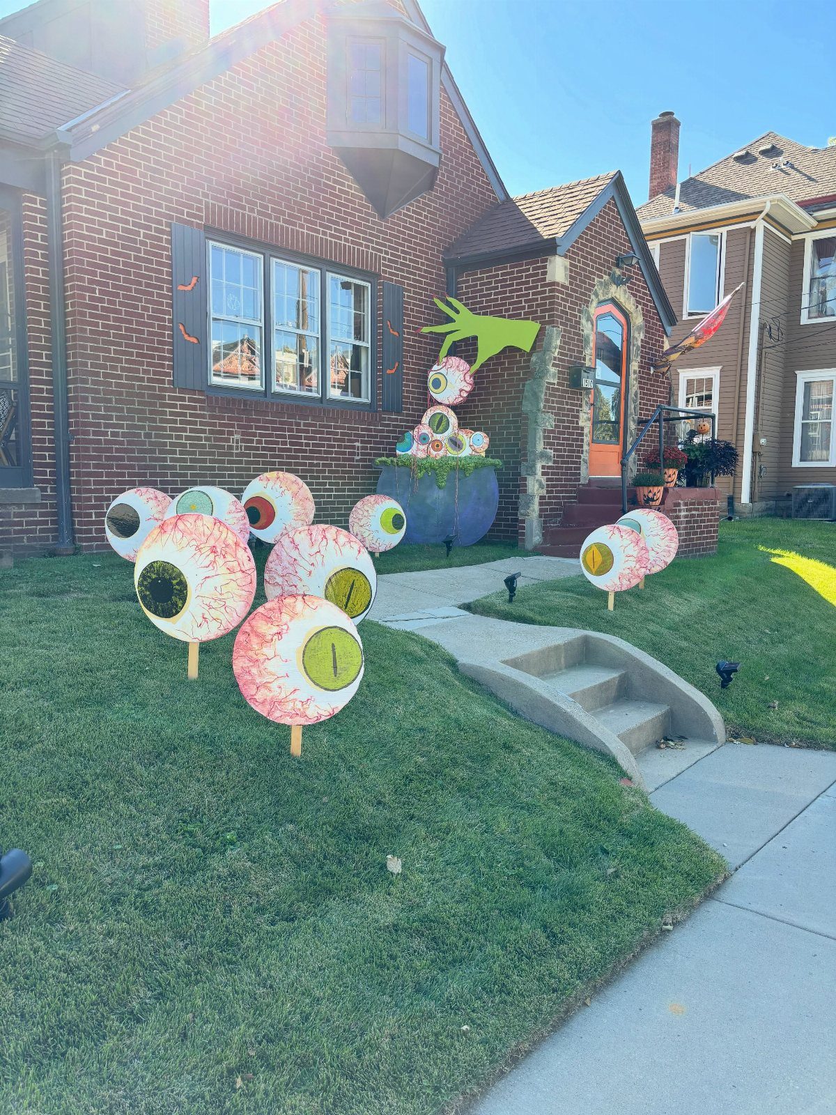 Large colorful DIY eyeballs on sticks decorating a green lawn in front of house