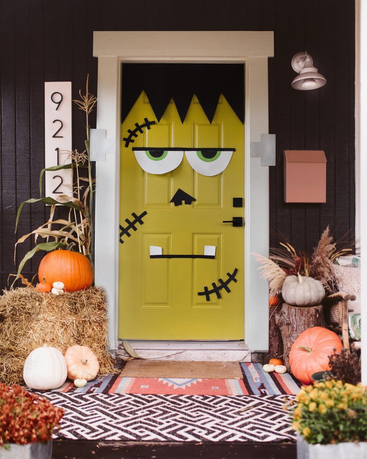 Frankenstein monster decorated lime green front door with pumpkins and hay bales on porch