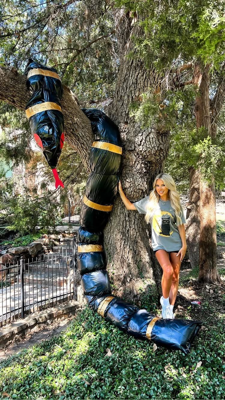 Woman posing next to black trash bag body bags tied with yellow tape outdoors