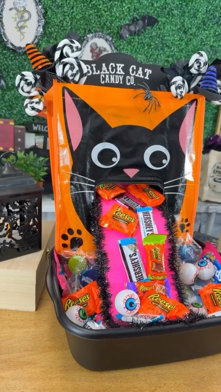 Black cat themed candy bin filled with assorted Halloween sweets and eyeball treats.