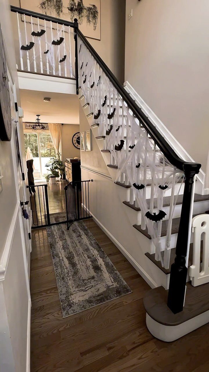 Staircase railing decorated with white spider webs and small black bat cutouts.
