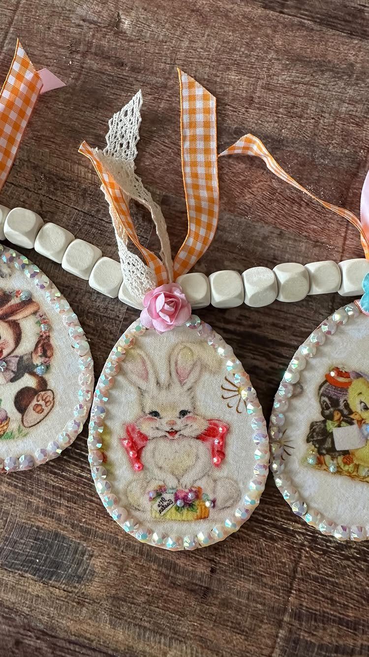 Three beaded oval bunny ornaments strung with white wooden beads and orange ribbons.