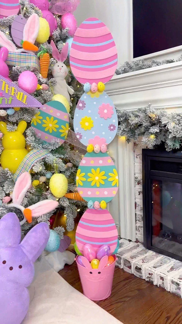 Stacked colorful decorative Easter eggs sitting in a pink bunny bucket by a tree.