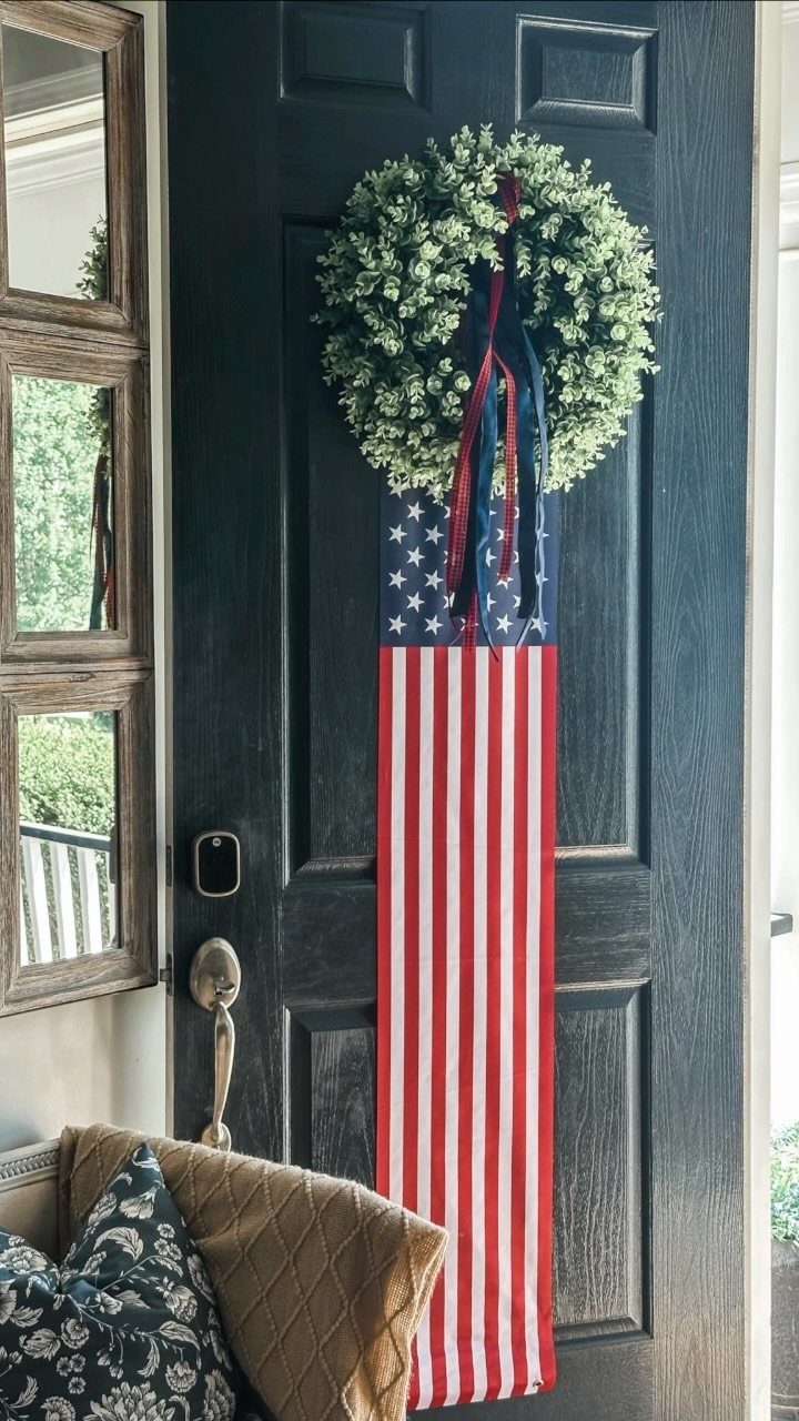 Green leafy wreath with a long American flag banner on a navy door