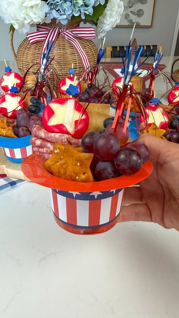 Red, white, and blue striped hat cup filled with grapes and crackers.